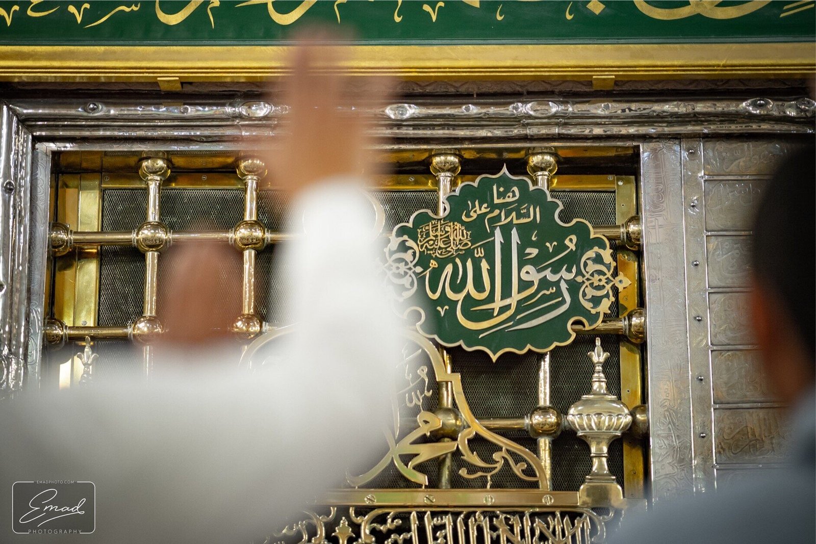 A pilgrim raising his hands at the golden Rawdah window