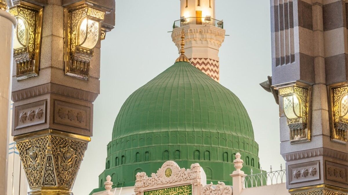 The Green Dome and a minaret of the Prophet's Mosque in Madinah framed by a striped stone arch