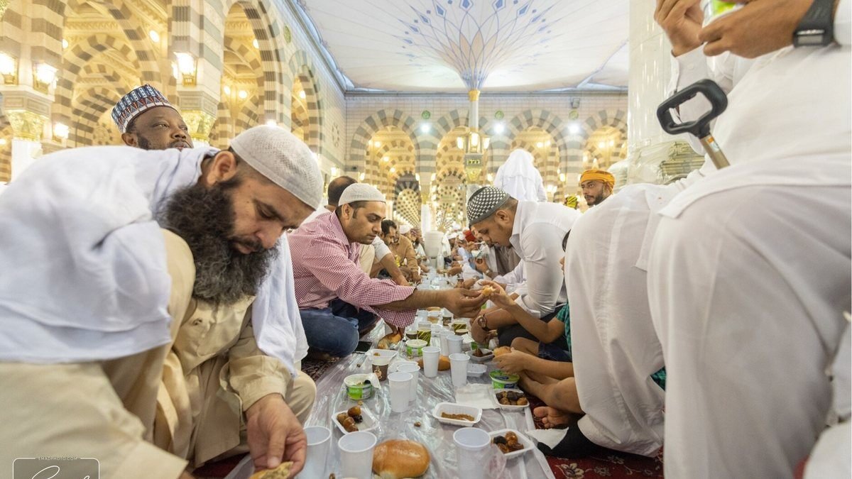 Pilgrims seated on the floor sharing an iftar meal inside the Prophet's Mosque in Madinah
