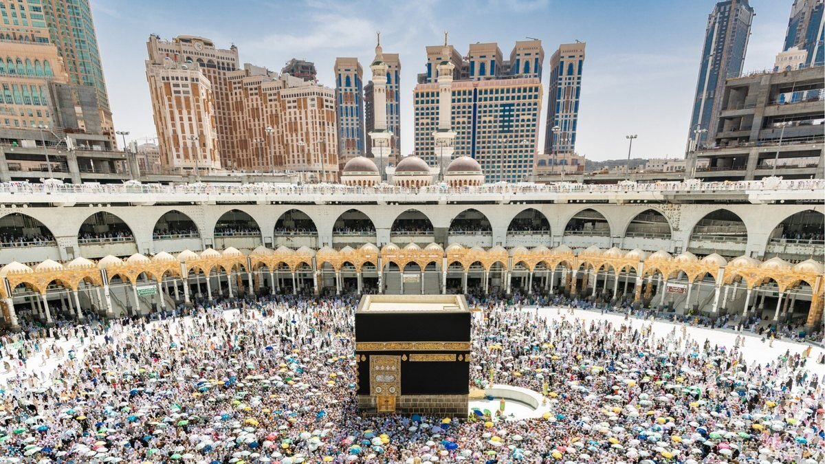 Packed mataf around the Kaaba at Masjid al-Haram, with the hotel towers of central Makkah behind