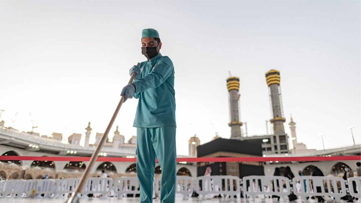 A cleaning worker on the Mataf floor of the Grand Mosque with the Kaaba behind him
