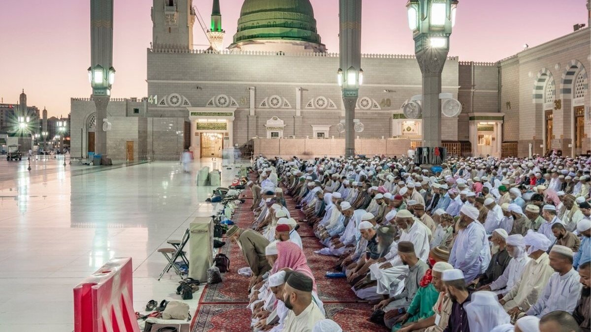 Worshippers in rows for the evening prayer in the courtyard of the Prophet's Mosque in Madinah at dusk